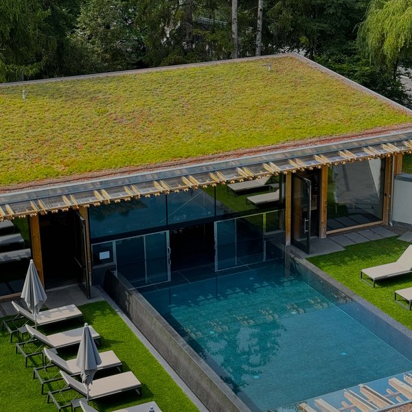 Von Wanderungen auf der Seiser Alm in die Spa Area Moderner Pool mit begrünter Dachterrasse und Sonnenliegen neben einem Wald