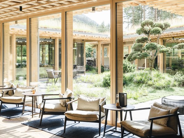 Wellness Aphrodite: Sensoria Dolomites unter den Siegern Gemütlicher Sitzbereich mit großen Glasfenstern und Blick auf Garten