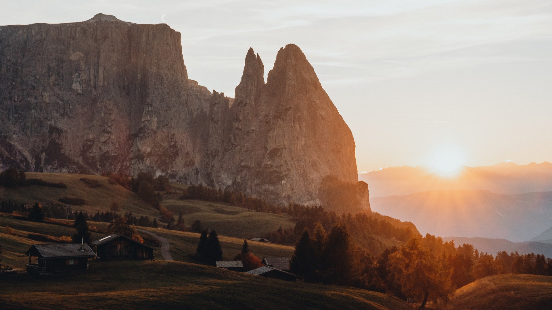 Ort der Kraft – Ihr Lieblingszimmer Sonnenuntergang hinter Felsspitzen in einer bergigen Landschaft mit Hütten