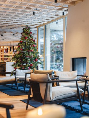Sensoria Dolomites: Wellnesshotel in den Dolomiten Gemütlicher Sitzbereich mit Weihnachtsbaum und Kamin in modernem Raum