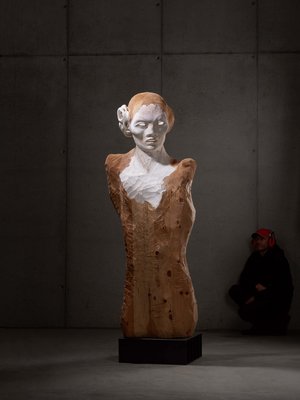 Sensoria Art Edition 01 Moderne Büste aus Holz und Stein in einem dunklen Raum, Mann sitzt im Hintergrund