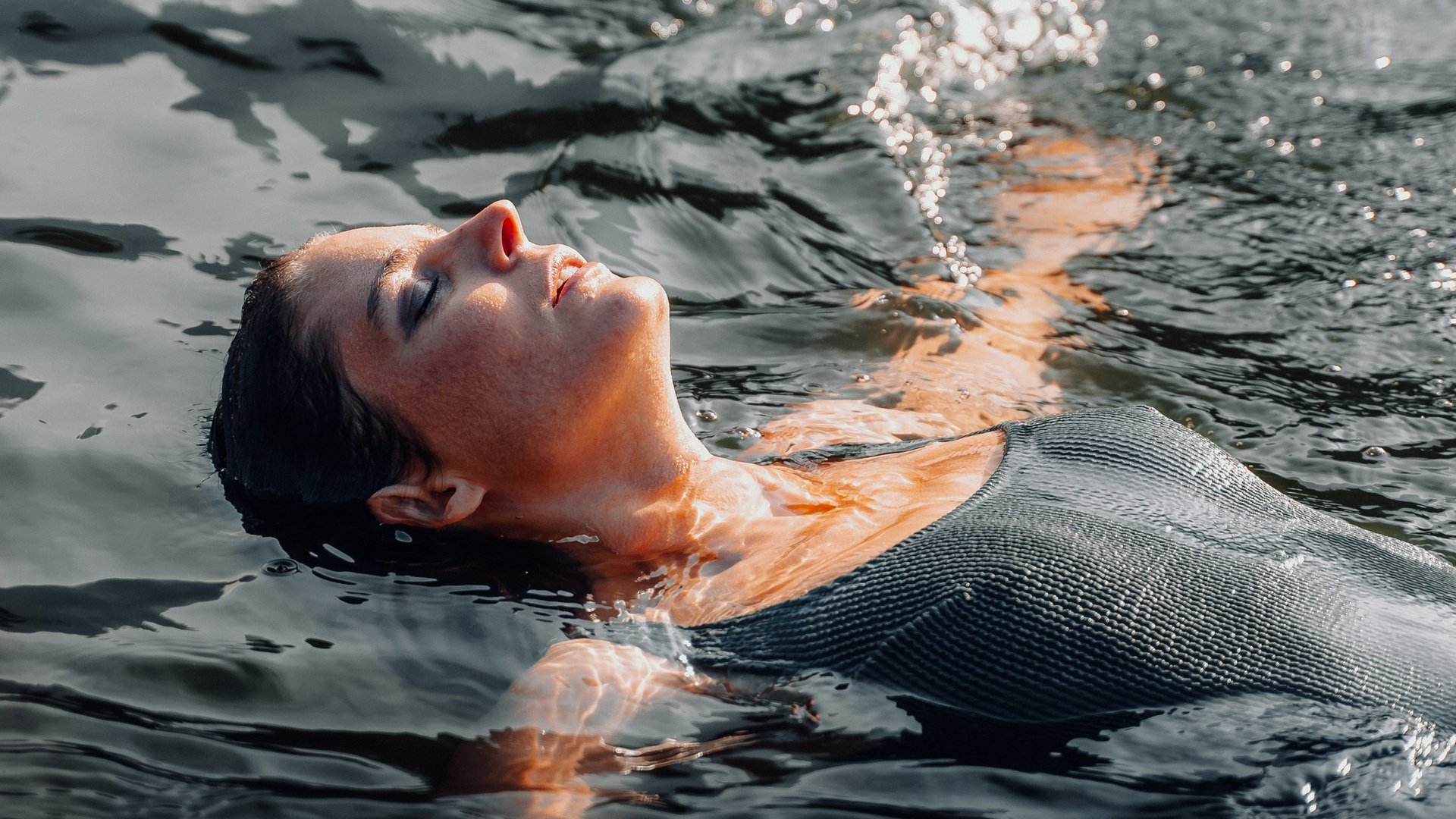 Luxus für die Seele im Kurzurlaub in Südtirol Frau entspannt beim Schwimmen und treibt auf dem Wasser