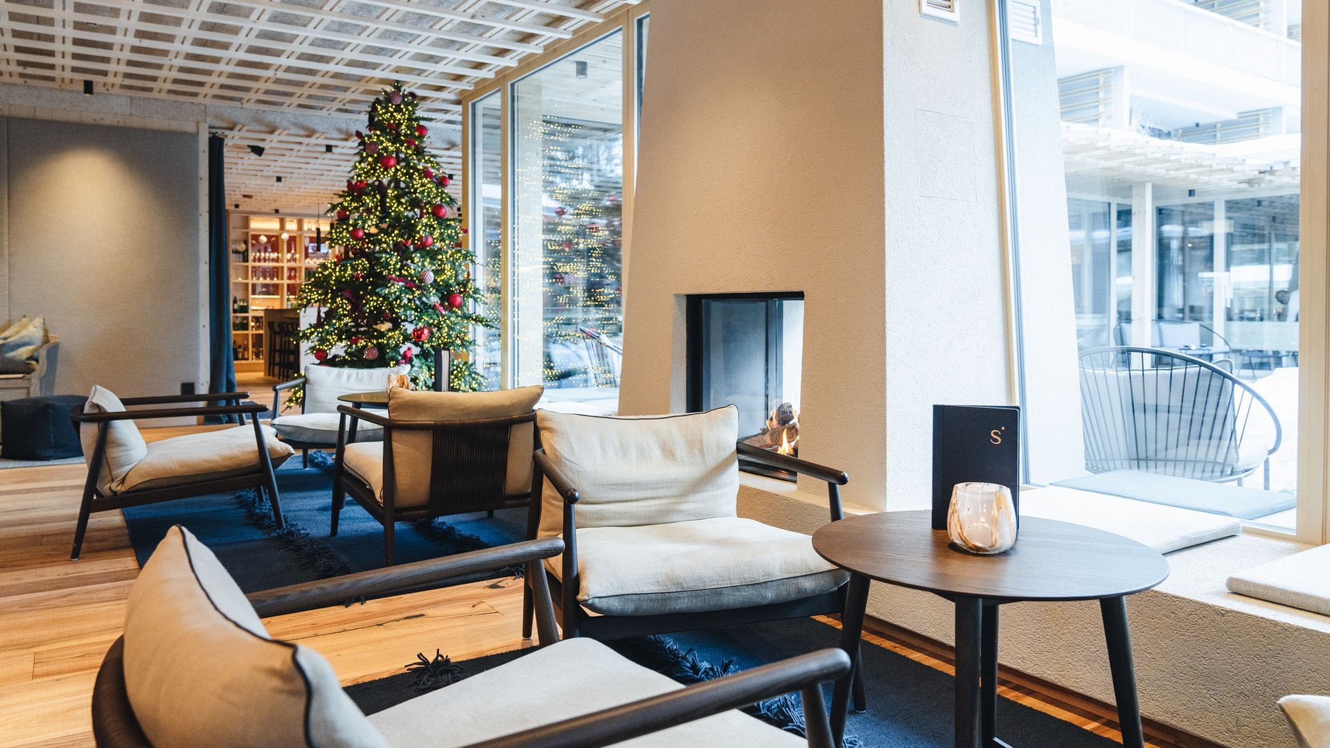 Sensoria Dolomites: Wellnesshotel in den Dolomiten Gemütlicher Sitzbereich mit Kamin und Weihnachtsbaum in modernem Hotel