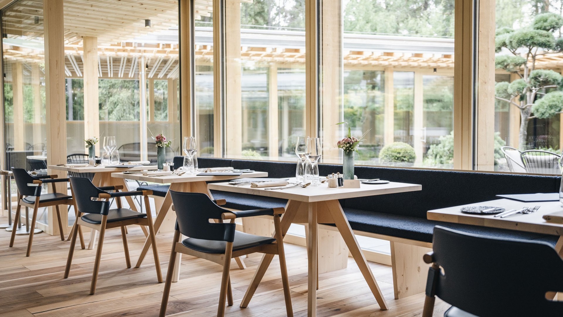 Genussurlaub in Südtirol – Sensoria Dolomites Modernes Restaurantinterieur mit Holzmöbeln und großen Fenstern