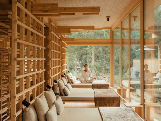 Luxus für die Seele: Ihr Yogahotel in Südtirol Person meditiert in modernem Holzraum mit Liegen und großer Fensterfront