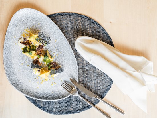 Luxus für die Seele im Kurzurlaub in Südtirol Elegantes Gericht mit dekorativem Teller, Besteck und gefalteter Serviette
