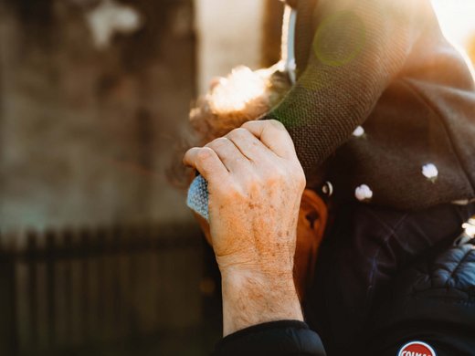 Nachhaltiges Handeln im Sensoria Dolomites Älterer Mann trägt Kind auf Schultern im Sonnenlicht