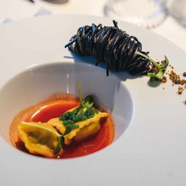 Genussurlaub in Südtirol – Sensoria Dolomites Feine Pasta mit roter Sauce und schwarzer Pastarolle auf weißem Teller