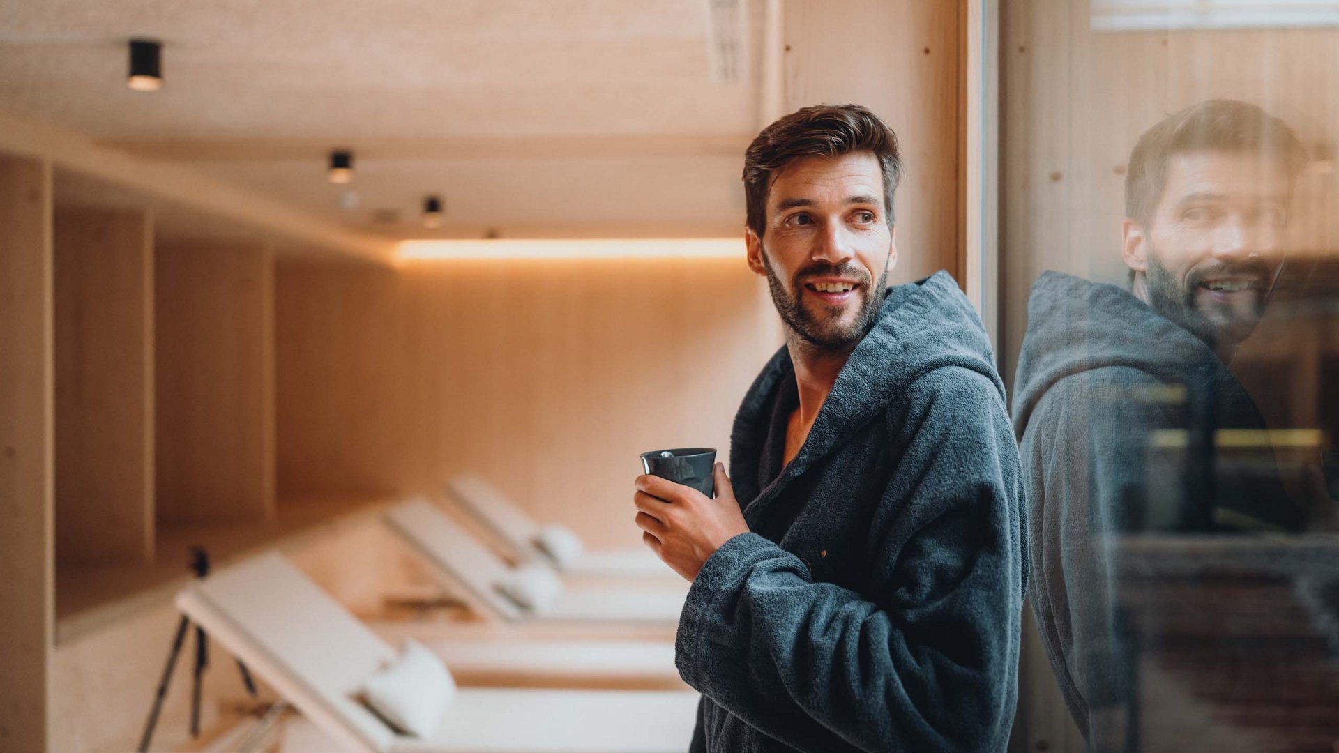 Von Wanderungen auf der Seiser Alm in die Spa Area Mann im Bademantel trinkt Kaffee in einem ruhigen Wellnessraum