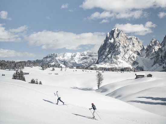 Seiser Alm: Skiurlaub de luxe Zwei Skifahrer in verschneiter Berglandschaft mit blauem Himmel und Bergen