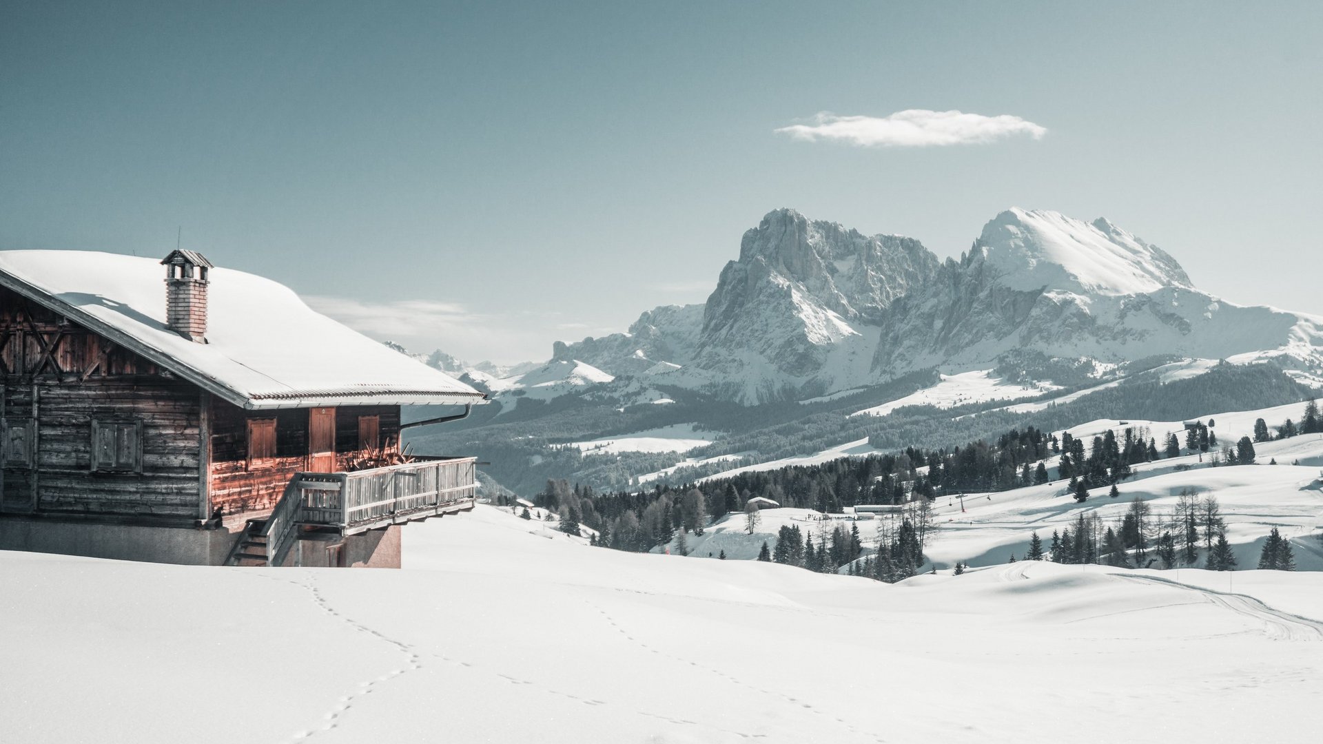 Seiser Alm: Skiurlaub de luxe Schneebedecktes Haus mit Bergen im Hintergrund bei klarem Himmel