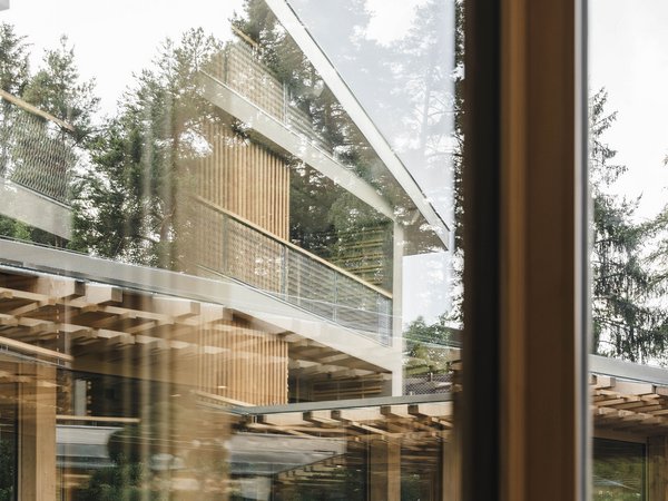 Wellness Aphrodite: Sensoria Dolomites unter den Siegern Moderne Glas- und Holzkonstruktion mit Bäumen im Hintergrund reflektiert