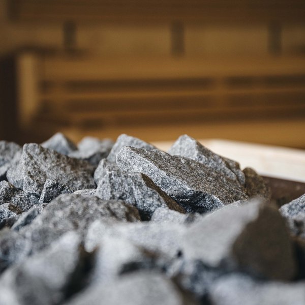 Your hotel in the Dolomites: Sensoria Dolomites Sauna stones in a sauna heater with wooden bench in the background