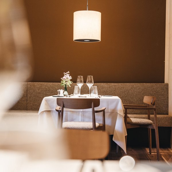 Your hotel in the Dolomites: Sensoria Dolomites Romantically set dining table with flower decoration under hanging lamp