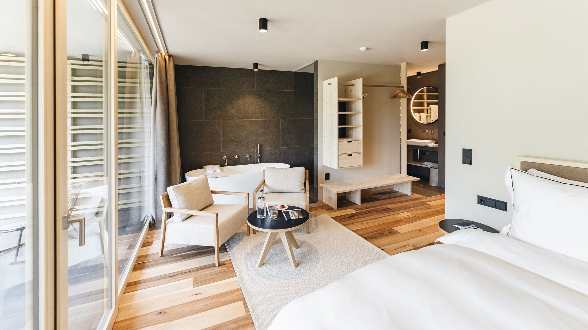 Your hotel in the Dolomites: Sensoria Dolomites Modern hotel room with bathtub, seating area, and large window