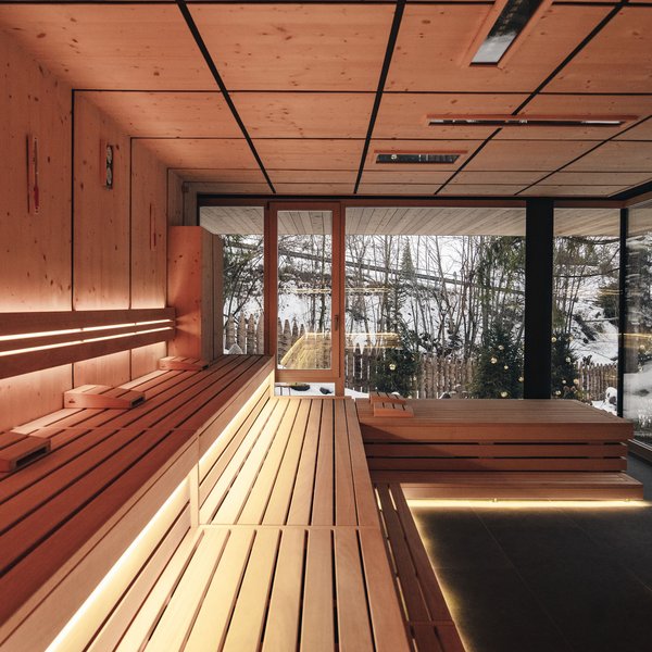Sensoria Dolomites: Wellnesshotel in den Dolomiten Moderne Sauna mit Holzinterieur und Blick auf verschneite Landschaft durch Glasfenster