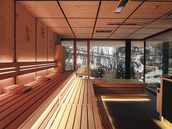 Sensoria Dolomites: Wellnesshotel in den Dolomiten Moderne Sauna mit Holzinterieur und Blick auf verschneite Landschaft durch Glasfenster