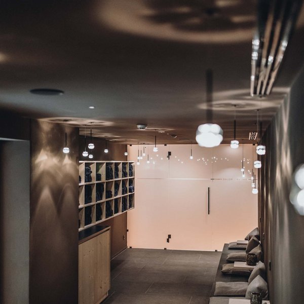 Your hotel in the Dolomites: Sensoria Dolomites Dimly lit hallway with bench and shelves in cozy spa area