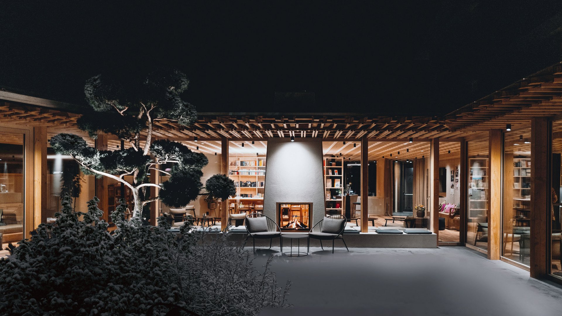 Sensoria Dolomites: Wellnesshotel in den Dolomiten Modernes Haus mit beleuchtetem Kamin und Garten bei Nacht