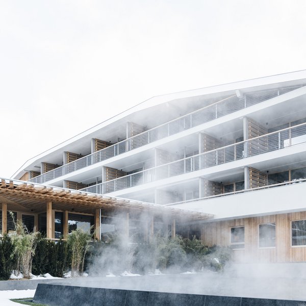 Sensoria Dolomites: Wellnesshotel in den Dolomiten Modernes Gebäude mit dampfendem Pool vor verschneiter Landschaft