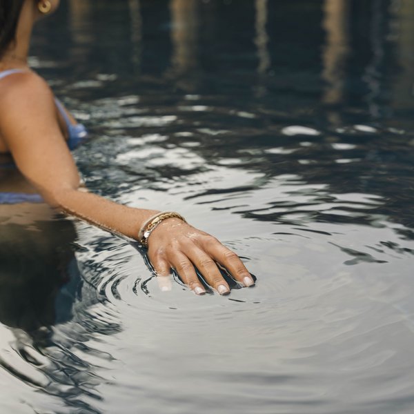 Your hotel in the Dolomites: Sensoria Dolomites Woman wearing bracelet touching water surface in pool