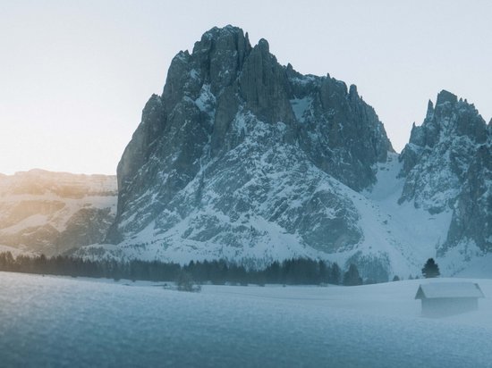 Sensoria Dolomites: Wellnesshotel in den Dolomiten Schneebedeckte Bergspitze bei Sonnenaufgang mit Holzhütte im Vordergrund