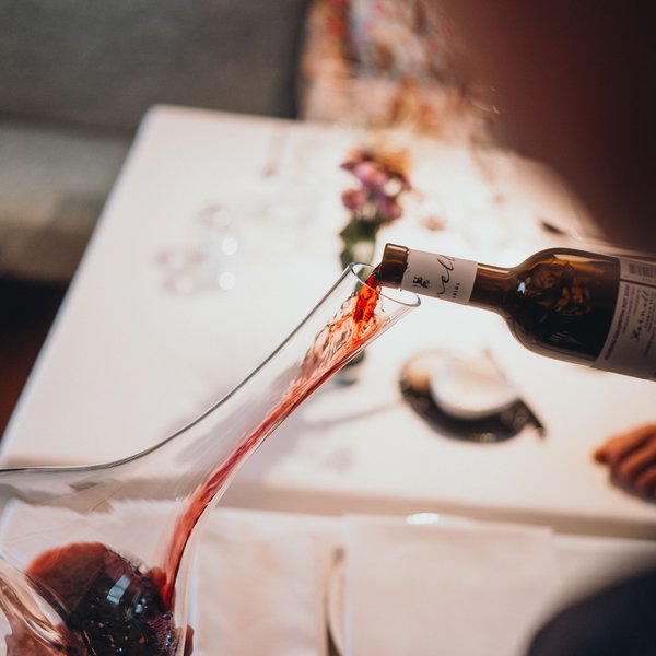 Sensoria Dolomites: Wellnesshotel in den Dolomiten Rotwein wird in eine Karaffe über einem weißen Tisch mit Servietten gegossen