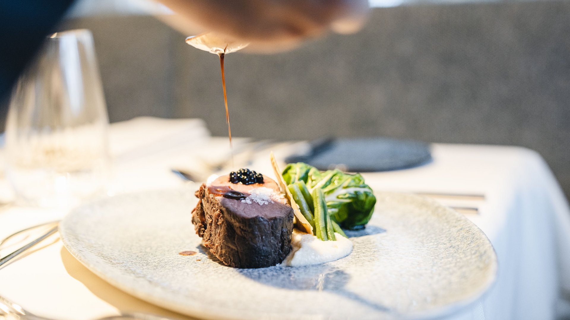 Sensoria Dolomites: Wellnesshotel in den Dolomiten Filetsteak mit Soße, grünem Gemüse und Sauce auf Teller