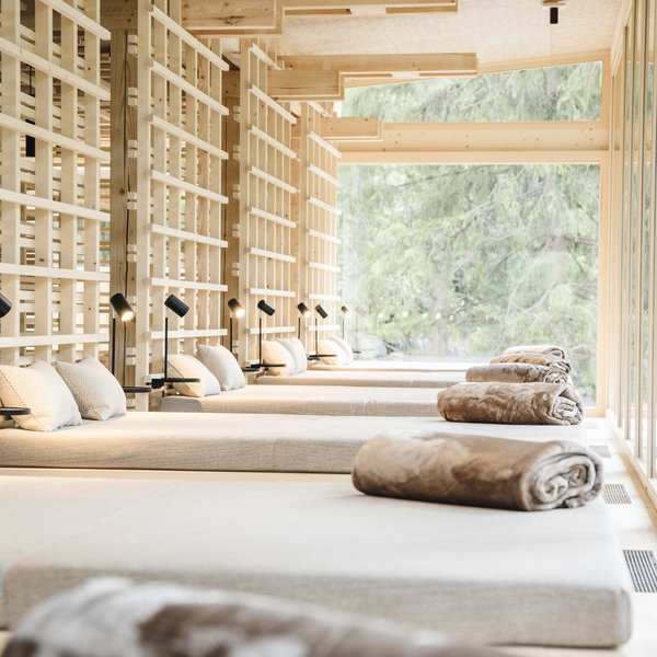 Your hotel in the Dolomites: Sensoria Dolomites Modern lounge beds with pillows and blankets in bright spa room with outdoor view