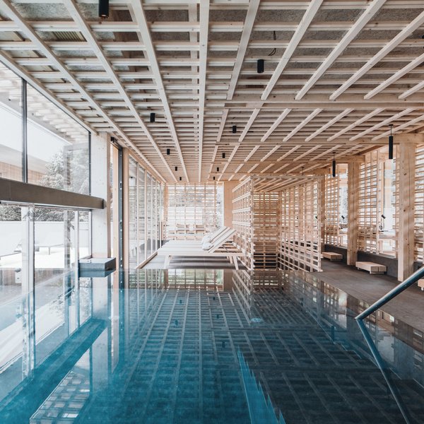 Sensoria Dolomites: Wellnesshotel in den Dolomiten Innenraum eines modernen Wellnesspools mit Holzdecke und Liegestühlen