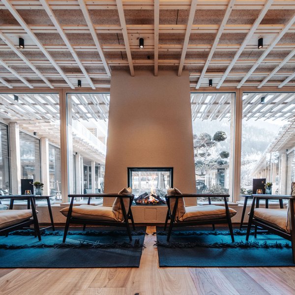 Sensoria Dolomites: Wellnesshotel in den Dolomiten Moderne Lounge mit Kamin, Holzdecke und großen Fenstern mit Bergblick