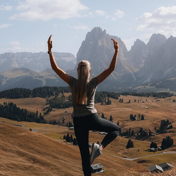 Your hotel in the Dolomites: Sensoria Dolomites Woman doing yoga in the mountains with view of valley and clear sky