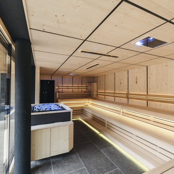 Your hotel in the Dolomites: Sensoria Dolomites Modern bright sauna with wooden benches and stone heater