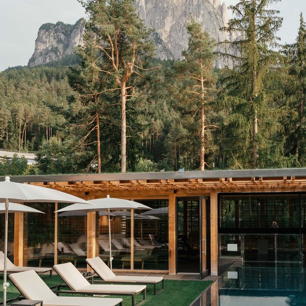 Your hotel in the Dolomites: Sensoria Dolomites Pool area with loungers and mountain view at a forest hotel