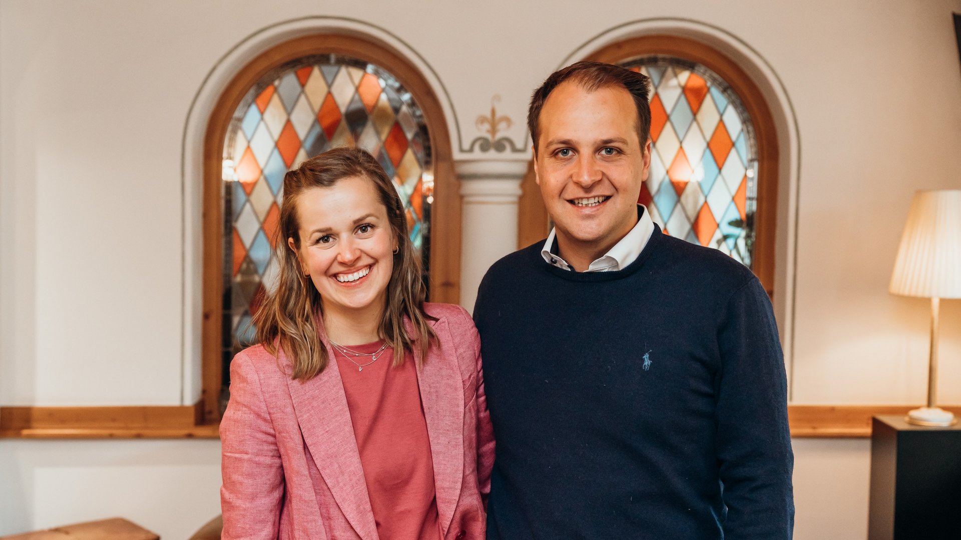 Places of spiritual power, favourite rooms, hosts with heart Smiling couple in front of colorful stained glass windows in cozy room