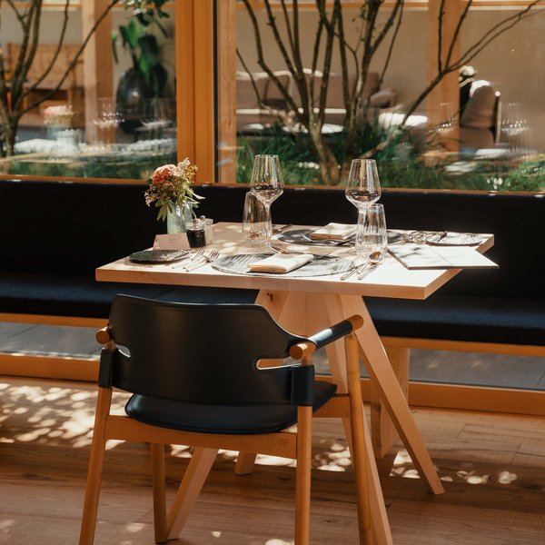 Your hotel in the Dolomites: Sensoria Dolomites Elegantly set table with glasses and flowers in bright restaurant