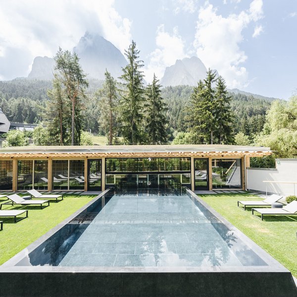 Your hotel in the Dolomites: Sensoria Dolomites Modern pool with loungers and mountain view on a sunny day