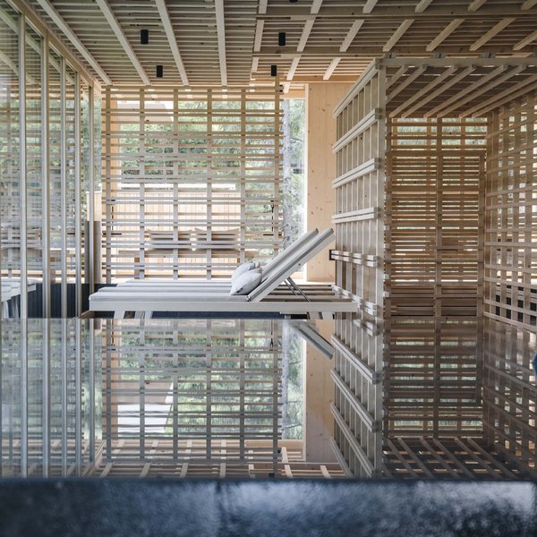 Your hotel in the Dolomites: Sensoria Dolomites Modern lounge chairs in a natural spa area with wood structures and water reflections